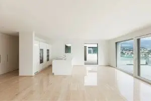 Empty modern living space with large windows, hardwood floors, and minimalistic design, relevant for discussing thermostat settings in unoccupied homes.