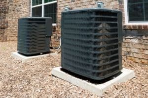Outdoor HVAC units positioned beside a brick house, surrounded by mulch, highlighting opportunities for creative holiday decorations.