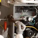 Technician servicing HVAC machinery with tools, emphasizing maintenance skills at Chad's AC Direct in Montgomery, Alabama.