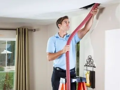 Man using a vacuum hose to clean air ducts, emphasizing the importance of duct cleaning for improved indoor air quality and HVAC efficiency.