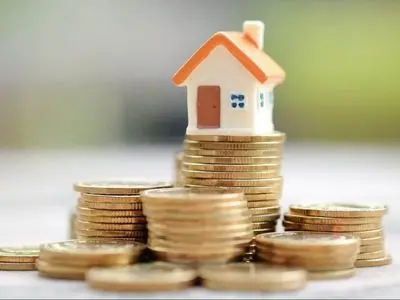 Model house on stacks of coins representing financial investment in home energy efficiency and HVAC upgrades.