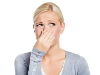 Woman covering her nose with a concerned expression, indicating potential air quality issues related to damaged air ducts.