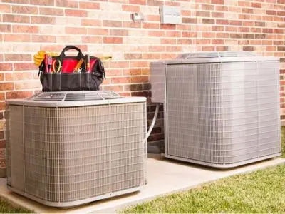 Air conditioning units with maintenance tools nearby, emphasizing the importance of efficient HVAC systems and reducing repair costs for homeowners.