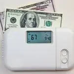 Digital thermostat at 67&deg;F with dollar bills, emphasizing HVAC service affordability at Chad's AC Direct, Montgomery, AL.