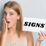 Young woman holding a "SIGNS" sign, emphasizing HVAC solutions from Chad's AC Direct.
