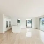 Modern open interior with a minimalist kitchen island and large glass windows, showcasing a bright, airy atmosphere.