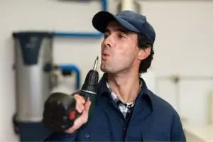 Man in a cap holding a power drill, symbolizing professional HVAC repair and quick solutions for furnace issues.