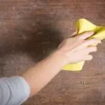 Hand cleaning a wooden surface with a yellow cloth, highlighting Chad's AC Direct's focus on maintenance and HVAC solutions.