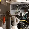 Technician repairing HVAC machinery with a wrench, showcasing hands-on technical expertise at Chad's AC Direct.