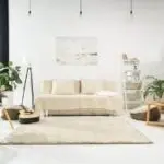 Modern minimalist living room featuring a sofa, light fixtures, plants, emphasizing air quality and comfort principles.