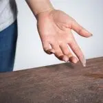 A human hand rests on a wooden surface, illustrating HVAC maintenance tips from Chad's AC Direct.
