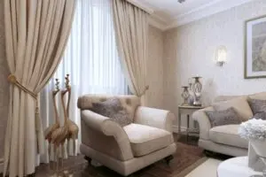Elegant living room featuring light-colored curtains and drapes, cozy armchairs, decorative accents, and natural light filtering through the windows, enhancing indoor comfort and energy efficiency.