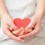 Adult and child hands holding a red heart cutout, emphasizing care and connection in HVAC home comfort services.