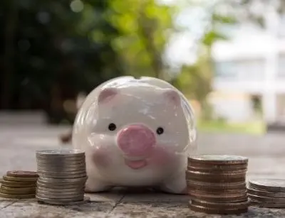 Piggy bank surrounded by stacks of coins, symbolizing energy savings and financial benefits from efficient heat pump systems.