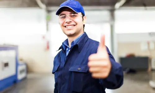 HVAC technician in uniform giving a thumbs up, showcasing professionalism and readiness for maintenance services.