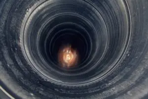 Close-up view of a dark, circular air duct interior, highlighting potential wear and tear, relevant to HVAC maintenance and efficiency in air conditioning systems.