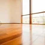 Empty room with hardwood flooring and large windows, showcasing ample natural light for a serene HVAC service setting.