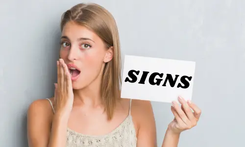 Woman holding a sign that reads "SIGNS," expressing surprise, in the context of identifying signs your HVAC unit needs replacement.