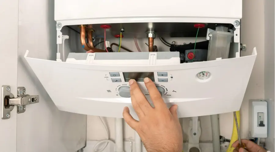 Hand adjusting settings on a modern boiler control panel, illustrating boiler maintenance and efficiency in home heating systems.