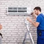 HVAC technician servicing air conditioning unit while homeowner observes, illustrating professional maintenance and repair services by Chris Wilson Plumbing & Heating Repairs Inc.