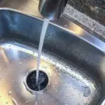 Stainless steel kitchen sink with faucet and flowing water, essential for plumbing maintenance by Chris Wilson Plumbing.