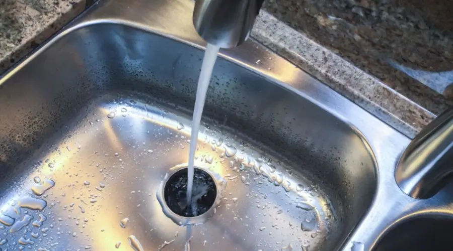 Stainless steel kitchen sink with faucet, water stream, granite countertop - Chris Wilson Plumbing service quality.
