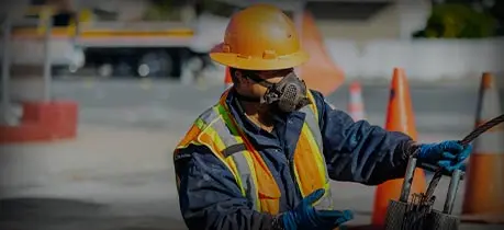 Construction worker in safety gear, inspecting plumbing equipment, emphasizing professional drain cleaning services and maintenance.