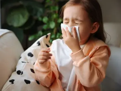 Child with a tissue experiencing allergy symptoms indoors, highlighting the health effects of poor indoor air quality.