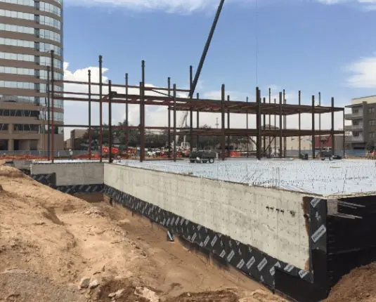 Construction site of the Barbara & George H.W. Bush Convention Center in Midland, Texas, featuring steel framework and foundation work, surrounded by machinery and ongoing development.