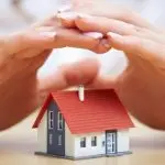 Hands protect a colorful miniature house, highlighting home maintenance and security for The Bosworth Company.