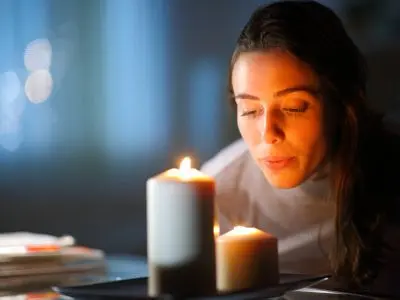 Woman blowing out candles on a plate, emphasizing safety by extinguishing flames before leaving home or going to bed.