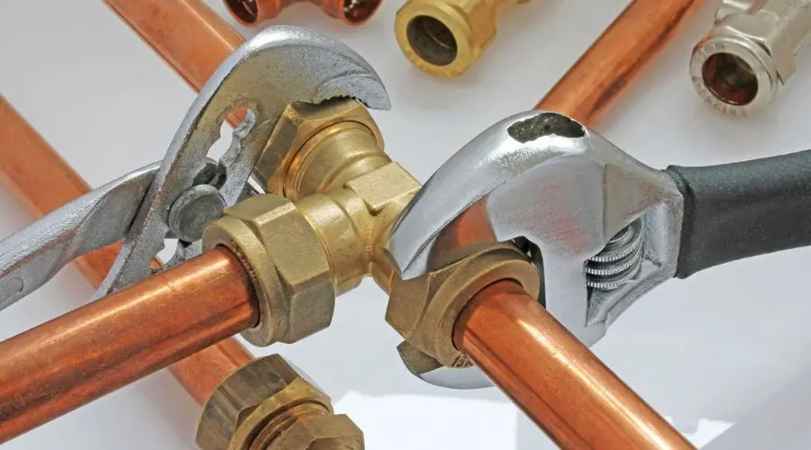Copper pipes and fittings with wrenches, tools for DIY home maintenance by a Midland HVAC expert.