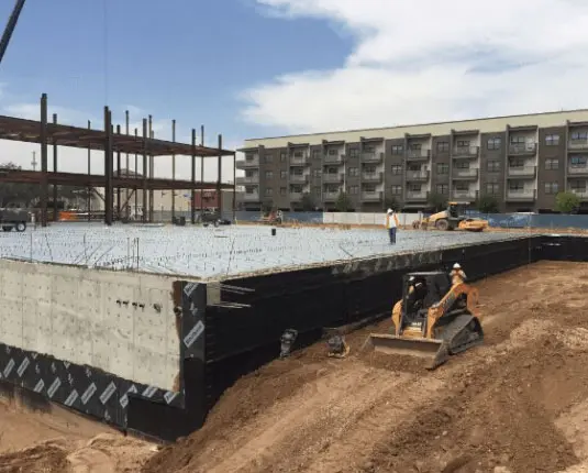 Construction site of the Barbara & George H.W. Bush Convention Center in Midland, Texas, featuring foundation work, construction workers, and machinery on-site.