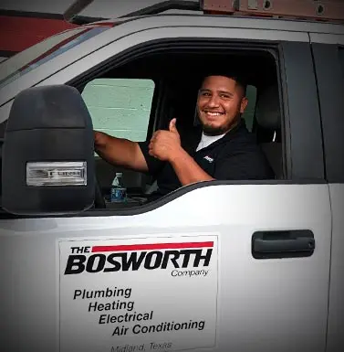 Smiling technician in The Bosworth Company truck, showcasing plumbing, heating, and air conditioning services in Midland, Texas.