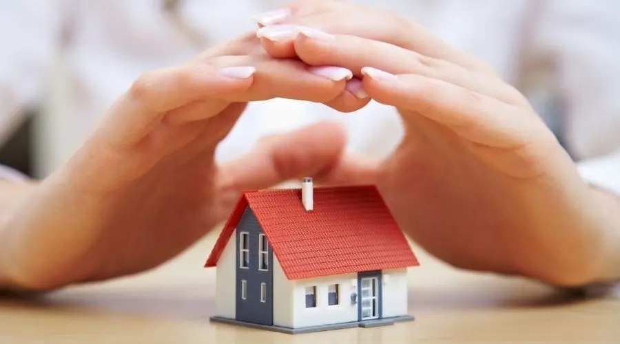 Miniature house model held in hands representing home protection and security by The Bosworth Company in Midland, TX.