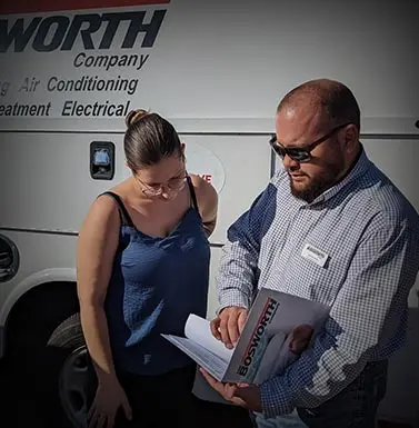 Man and woman discussing service options in front of a Bosworth Company vehicle, highlighting HVAC and electrical services.
