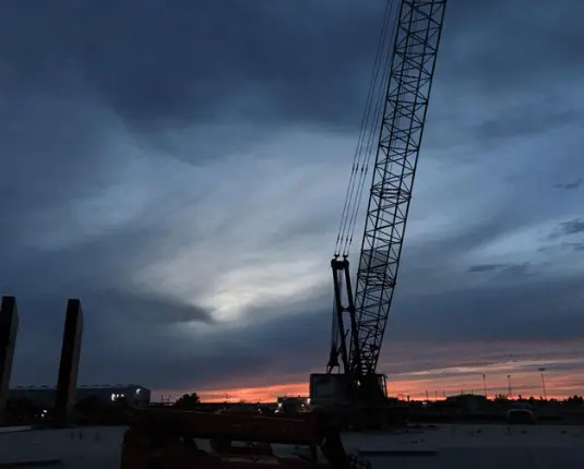 Crane silhouetted against a sunset sky at the construction site of Odessa Christian Faith Center, highlighting The Bosworth Company's involvement in the project.