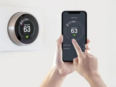 Smart thermostat installation with user adjusting settings on smartphone, showcasing energy-efficient temperature control.