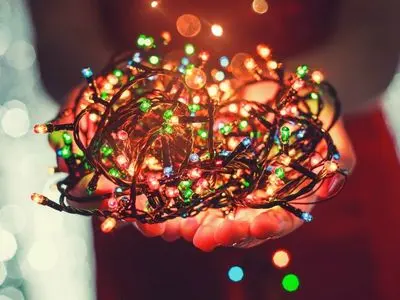 Colorful LED Christmas lights held in hands, showcasing energy-efficient holiday decorations, emphasizing savings and safety during the festive season.