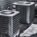 Two air conditioning units on a concrete patio, showcasing HVAC solutions by The Meridian Company for home comfort.