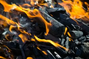 Burning charcoal with flames, representing heating solutions and energy efficiency in HVAC services.