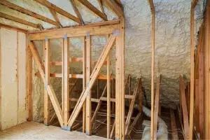Interior of an attic with wooden framing and spray foam insulation, highlighting HVAC efficiency improvements.