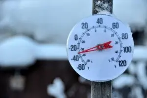 Outdoor thermometer displaying sub-zero temperatures surrounded by snow, emphasizing the importance of furnace maintenance during winter.