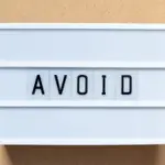 Lightbox display with the word "AVOID" in black on white, against a brown background, relating to HVAC caution.