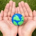 Human hands holding a blue and green globe, showcasing Earth with landmasses; emphasizes HVAC and environmental awareness.