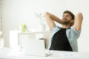 Man relaxing at a desk with a laptop, emphasizing comfort and well-being in a workspace, relevant to HVAC and indoor air quality.