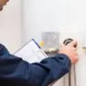 Technician inspecting electrical panel with tools, emphasizing safety for home service maintenance by The Meridian Company.