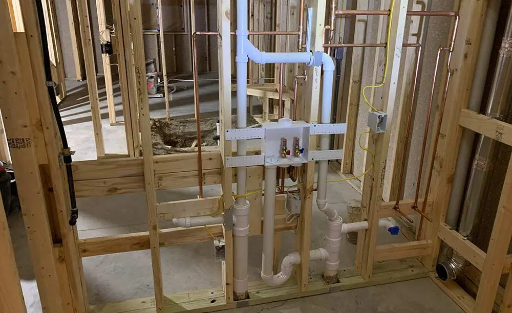 Repiping installation showcasing copper and PVC pipes in a residential construction setting, illustrating plumbing solutions by The Meridian Company.