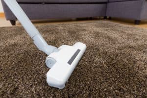 Vacuum cleaner on brown carpet in a living room setting, emphasizing home cleaning for fall maintenance tips.