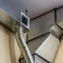 Metallic air ducts and ventilation system with textured ducting and grille vent for HVAC efficiency.